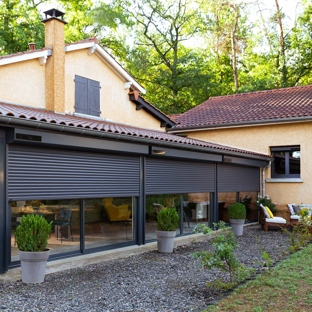 Grote zwarte solar rolluiken op een woning met tuin
