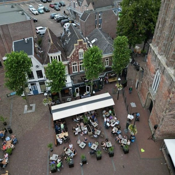 Terras met zon- en regenscherm in druk stadsplein
