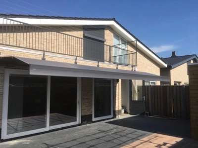 Zon- en regenscherm boven terras aan huis, biedt schaduw en bescherming Zon- en regenscherm boven terras aan huis, biedt schaduw en bescherming