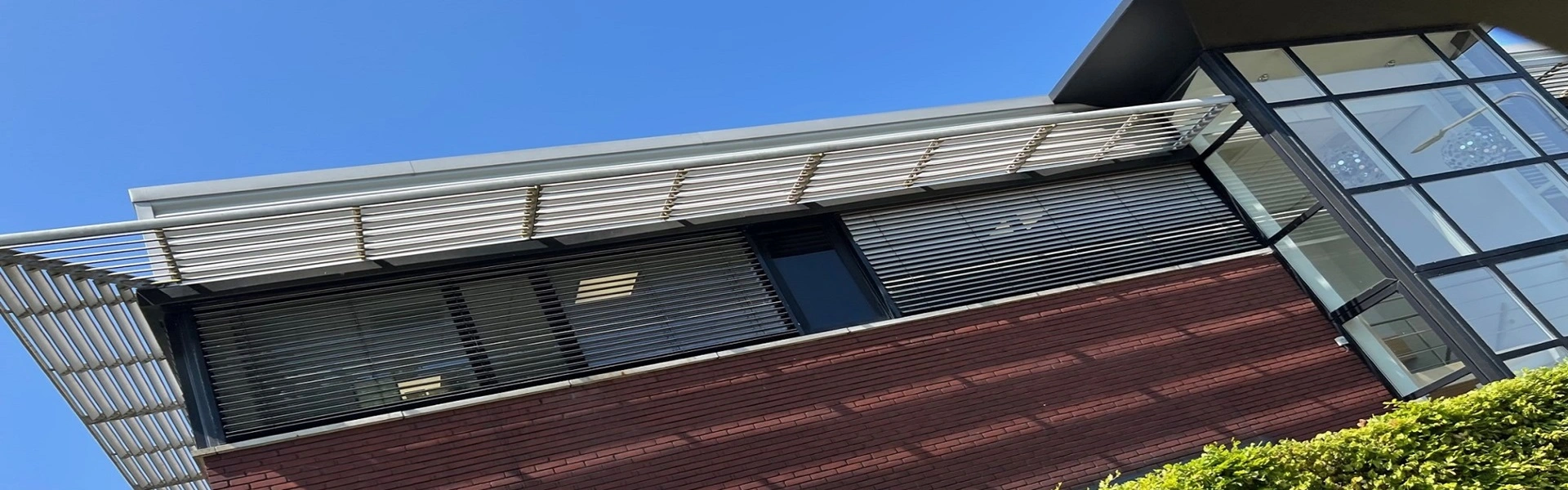 Buitenjaloezieen op kantoorgebouw met glazen en rode bakstenen gevel