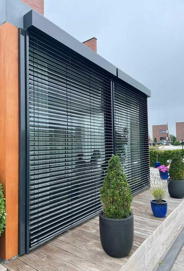 Close-up van zwarte buitenjaloezieen met planten in bloempotten op een houten terras Close-up van zwarte buitenjaloezieen met planten in bloempotten op een houten terras