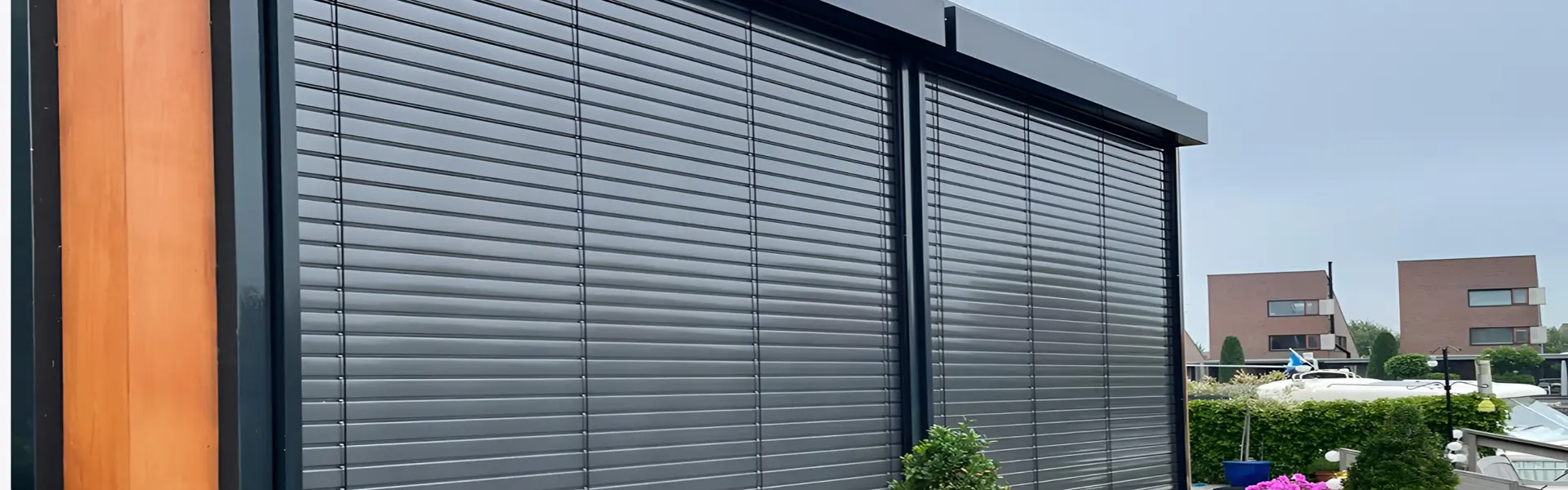 Gesloten buitenjaloezieen met houten geveldetail en uitzicht op woningen Gesloten buitenjaloezieen met houten geveldetail en uitzicht op woningen