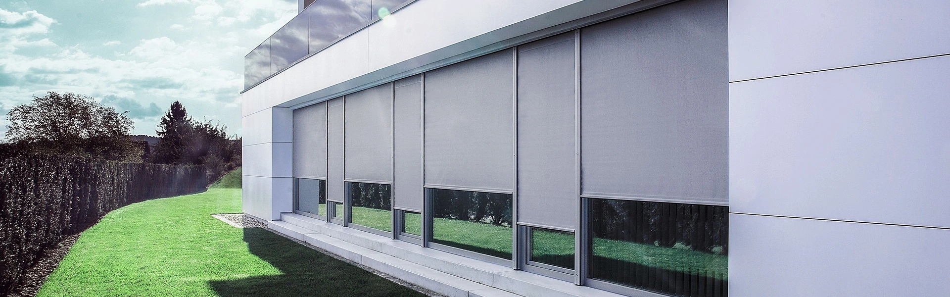 Gevel met grijze screens in een groene omgeving