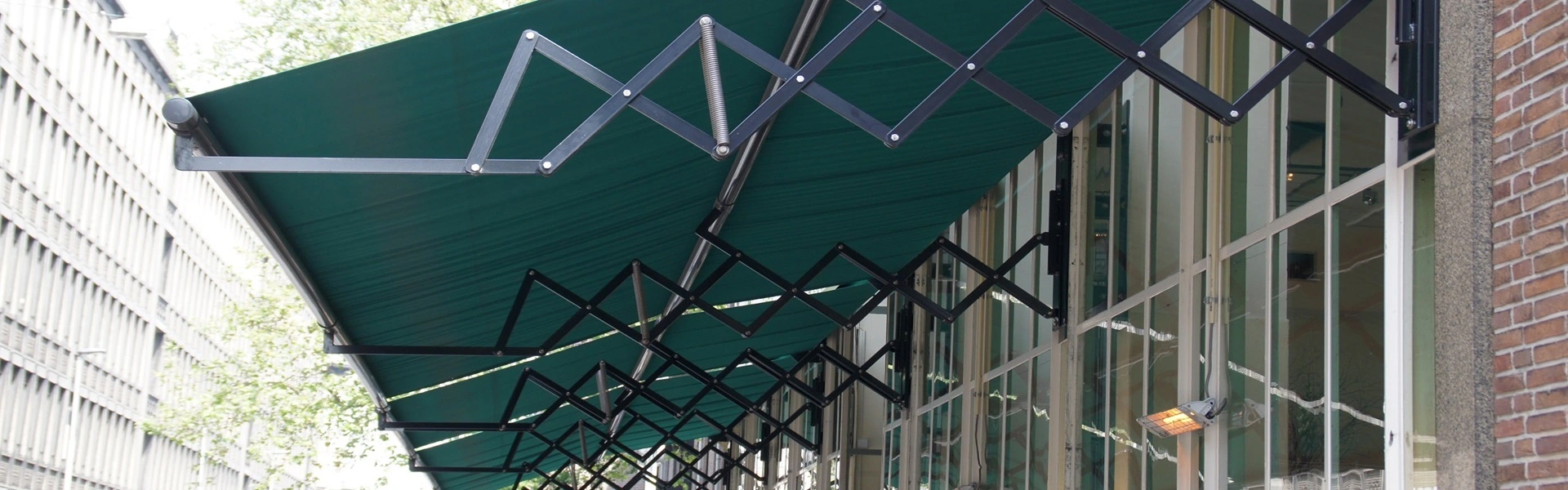 Groen schaararmscherm boven horecagevel