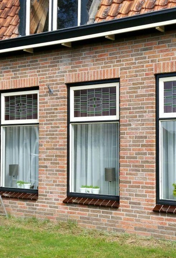 Groen-wit gestreepte markiezen aan voorzijde van karakteristieke woning Groen-wit gestreepte markiezen aan voorzijde van karakteristieke woning
