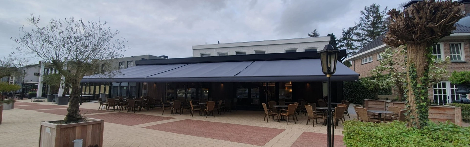Groot schaararmscherm XXL beslaat een ruime horecaruimte, ideaal voor zonwering