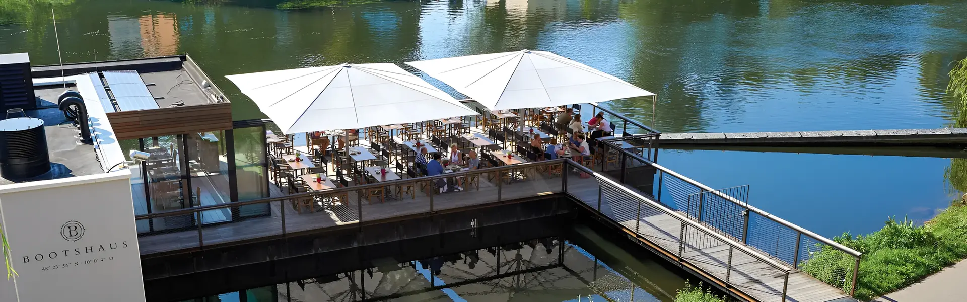 Grote witte parasols bieden schaduw op terras aan het water