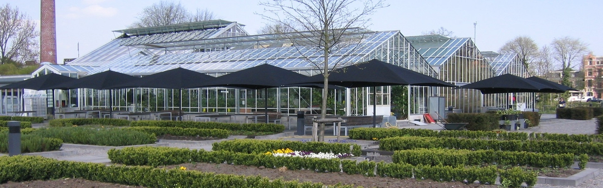 Grote zwarte parasols bij kasrestaurant omgeven door bloemperken