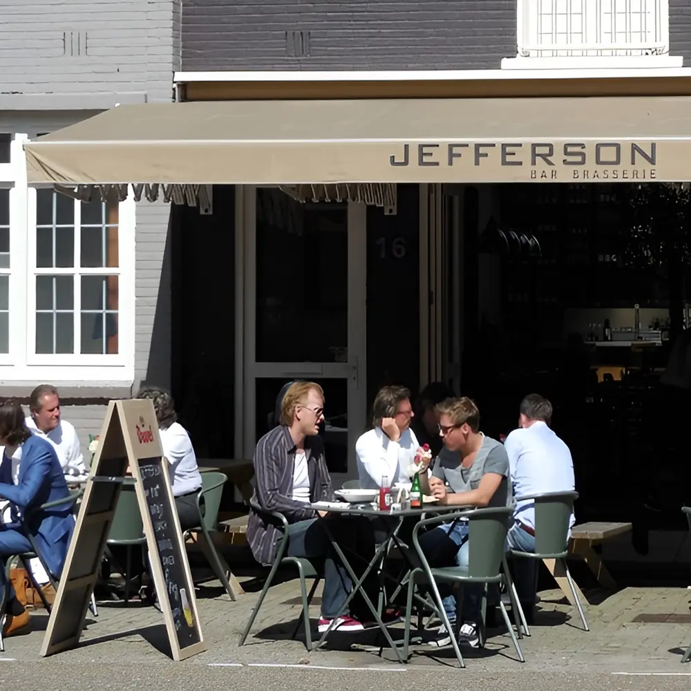 Jefferson Brasserie met schaduw van schaararmscherm en gasten op terras