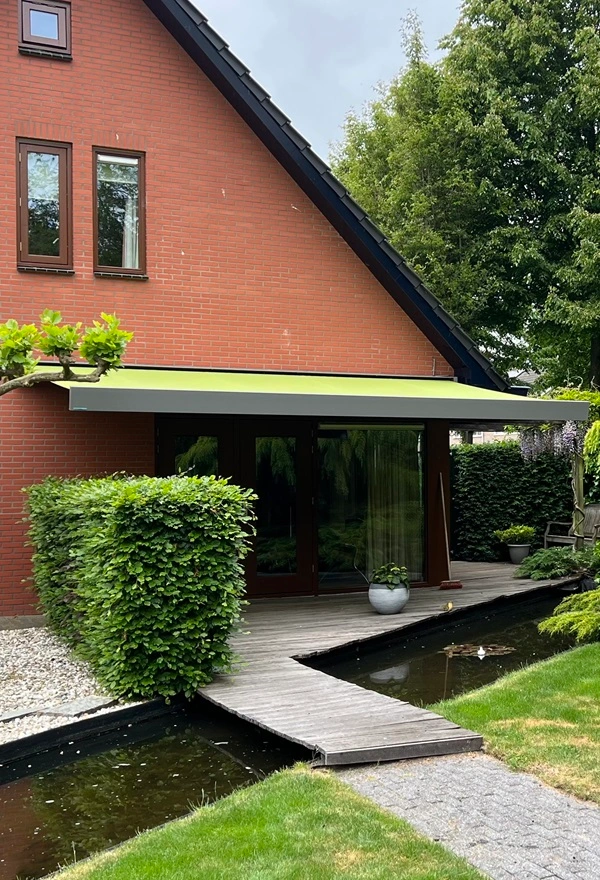 Knikarmscherm aan huis met vijver en tuinpad Knikarmscherm aan huis met vijver en tuinpad