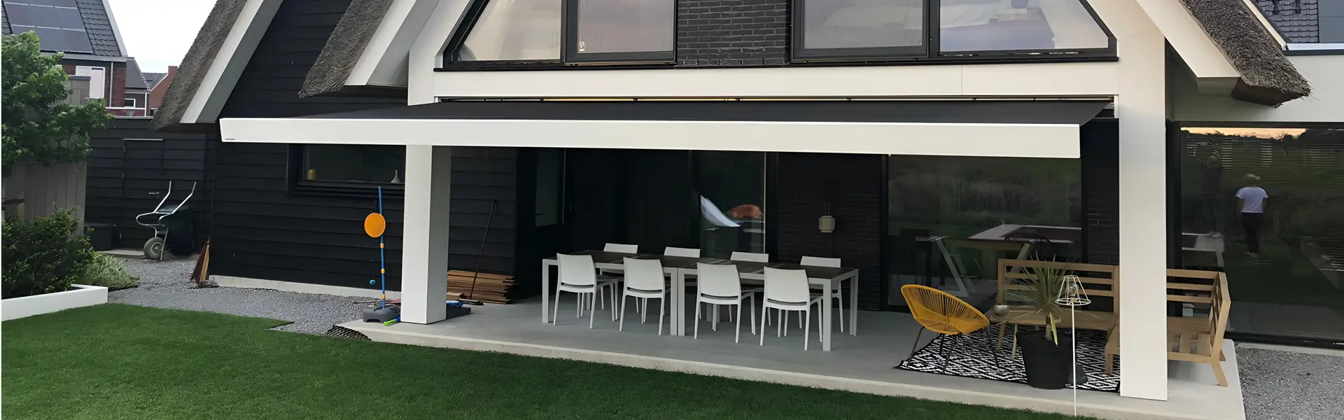 Knikarmscherm boven terras met eettafel en stoelen Knikarmscherm boven terras met eettafel en stoelen