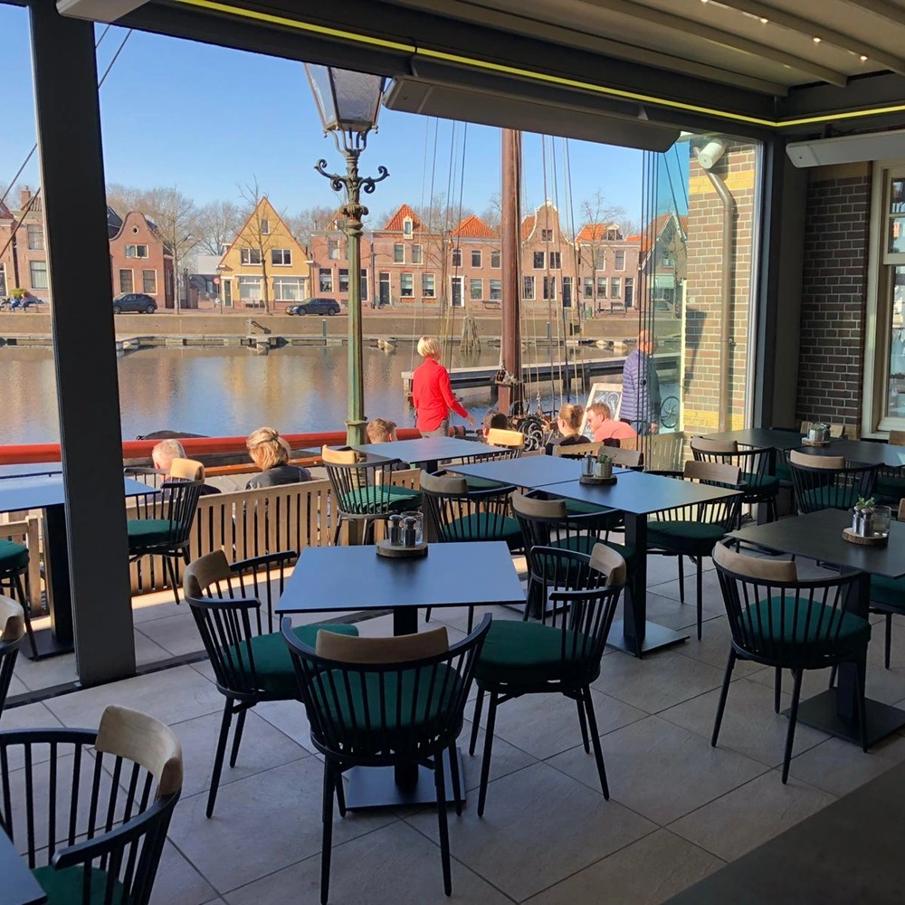 Overdekt terras met glazen schuifwanden en zicht op historische panden