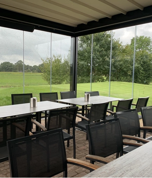 Overdekt terras met glazen wanden bij golfbaan