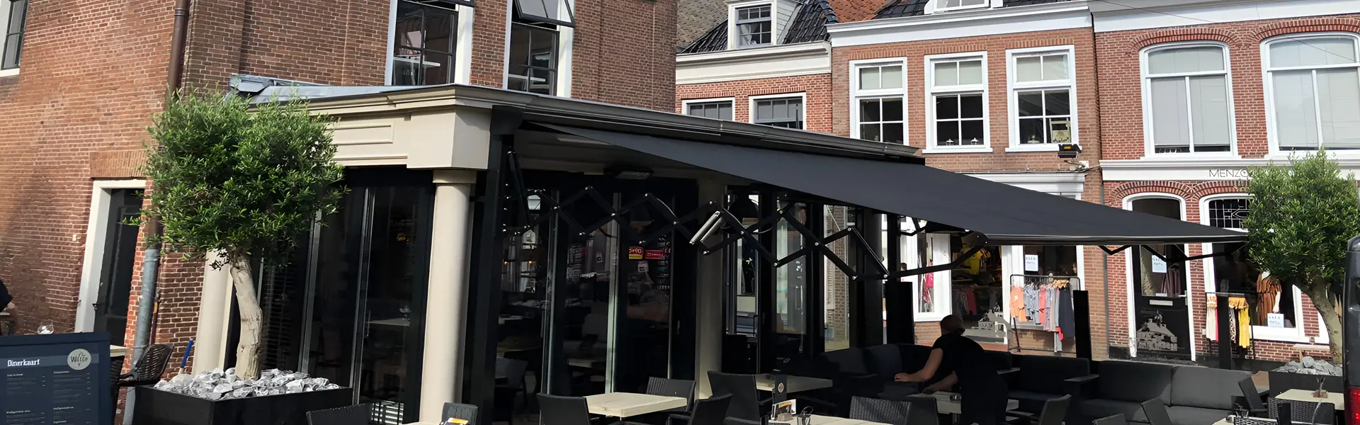 Schaararmscherm biedt elegante zon- en regenwering bij horecaterras