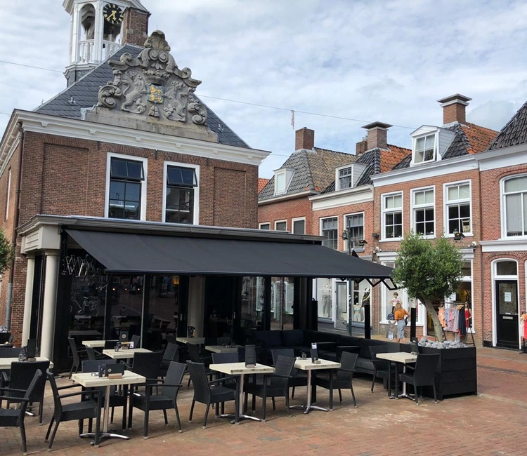 Schaararmscherm biedt schaduw aan terras voor historisch gebouw in stadscentrum