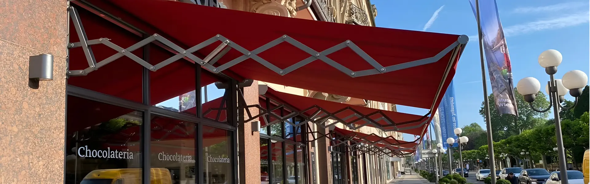 Schaararmscherm bij horecagevel met opvallende rode doek