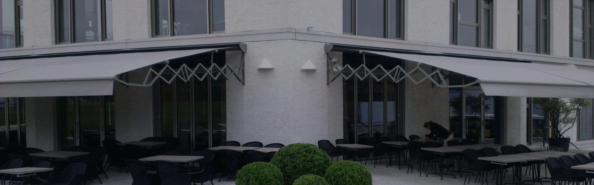 Schaararmscherm boven terras van witte horecagevel