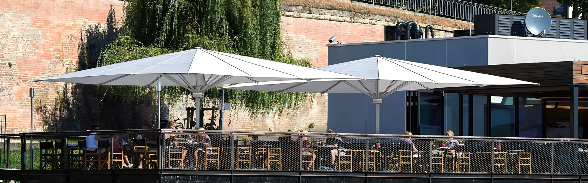 Schaduwrijke zitplaatsen onder stijlvolle parasols aan de rivier