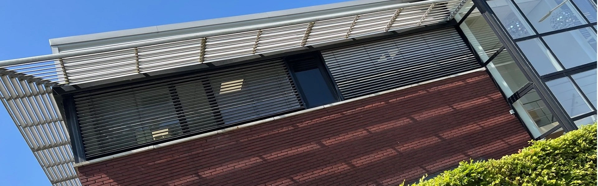 Schuin aanzicht van buitenjaloezieen en glazen gevel bij Nationale Fietsprojecten Schuin aanzicht van buitenjaloezieen en glazen gevel bij Nationale Fietsprojecten