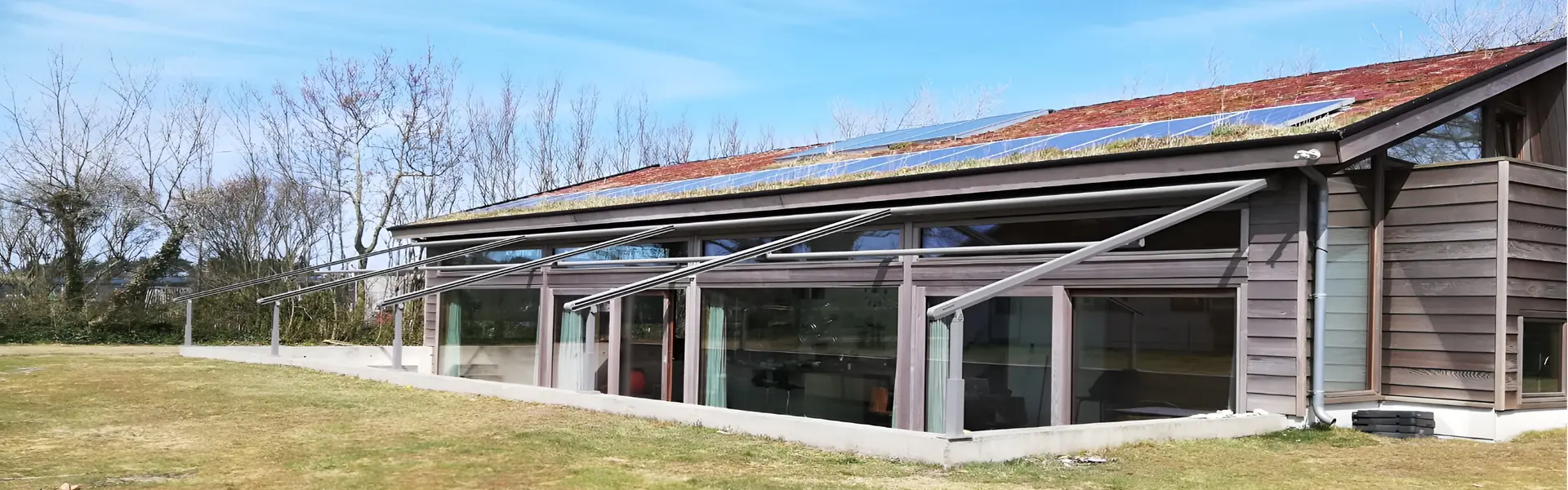 Schuine overkapping met doek en zonnepanelen op een groen perceel