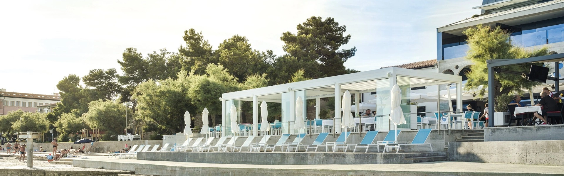 Strandhotel met terrasoverkapping en ligstoelen aan het water