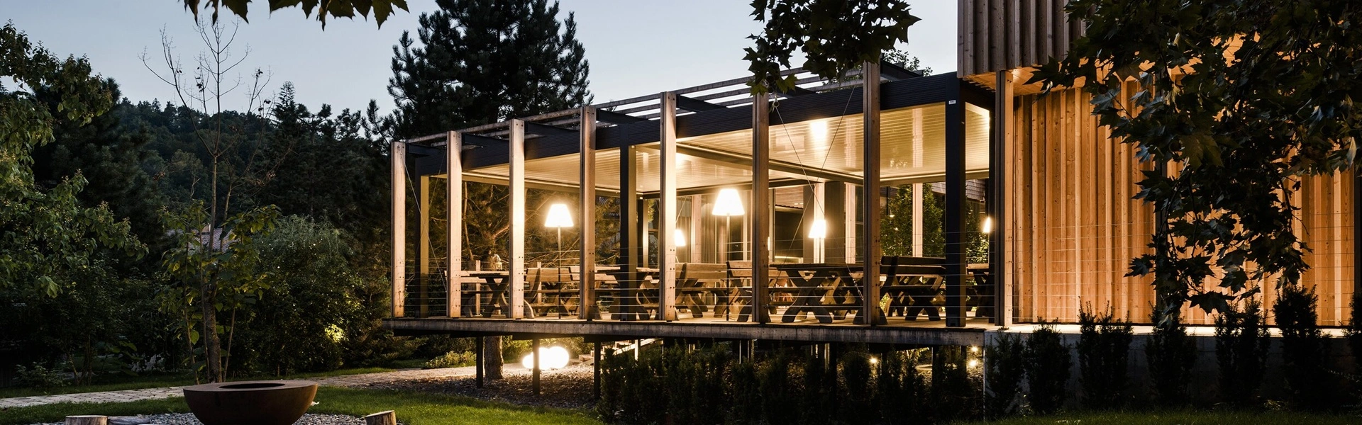 Verlichte terrasoverkapping met houten constructie en avondlicht