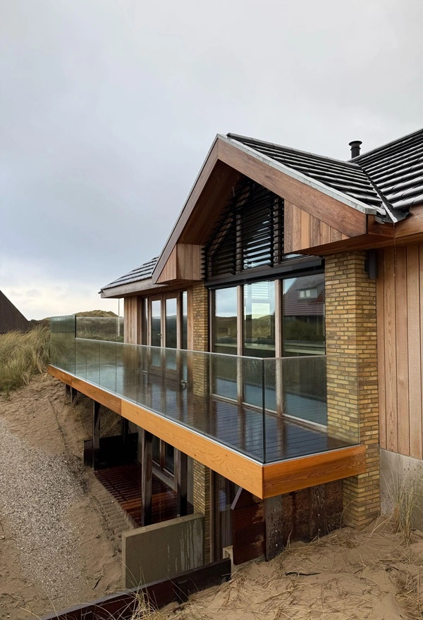 Villa met houten gevelbekleding, glazen balkon en zonwerende louvre lamellen Villa met houten gevelbekleding, glazen balkon en zonwerende louvre lamellen