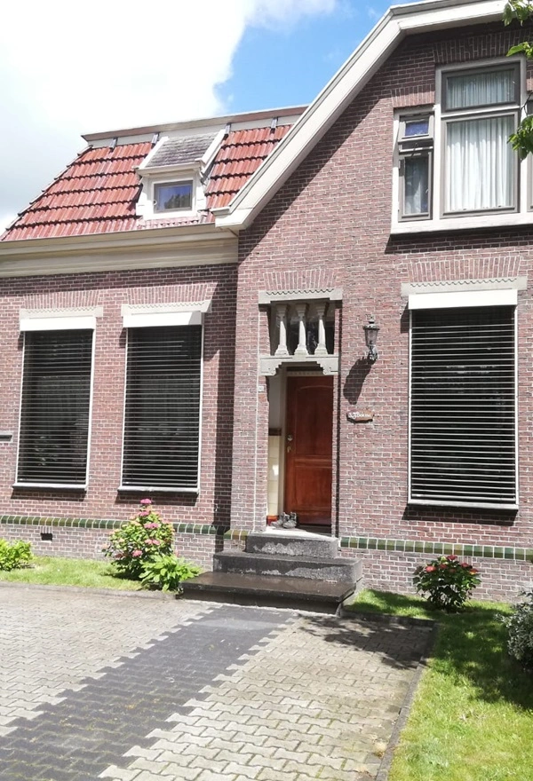 Voorgevel met buitenjaloezieen gesloten voor privacy en zonwering Voorgevel met buitenjaloezieen gesloten voor privacy en zonwering