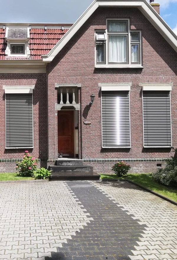 Voorgevel met buitenjaloezieen half geopend voor optimale lichtinval Voorgevel met buitenjaloezieen half geopend voor optimale lichtinval