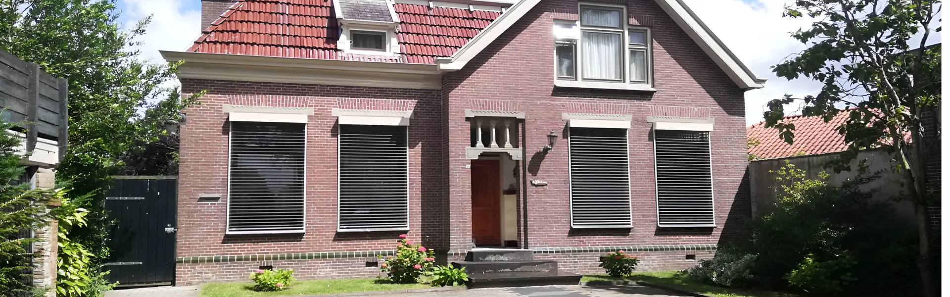 Voorgevel van woning met buitenjaloezieën voor zonwering en privacy Voorgevel van woning met buitenjaloezieën voor zonwering en privacy