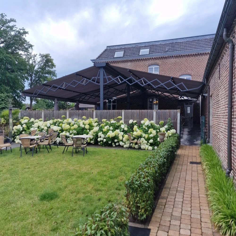 Vrijstaand schaararmscherm Vertigo over terras met tuin en zitplaatsen
