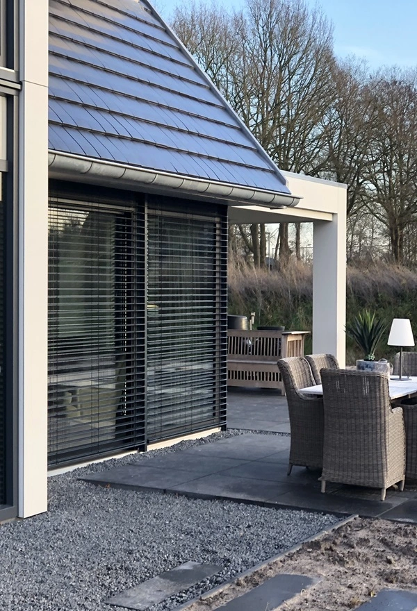 Zijaanzicht van buitenjaloezie en houten gevel bij woning in Joure Zijaanzicht van buitenjaloezie en houten gevel bij woning in Joure