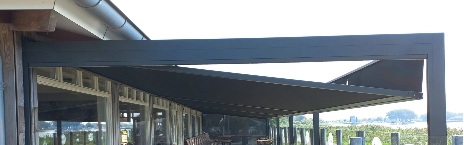 Zonwering met glazen panelen voor terrasuitbreiding aan het water