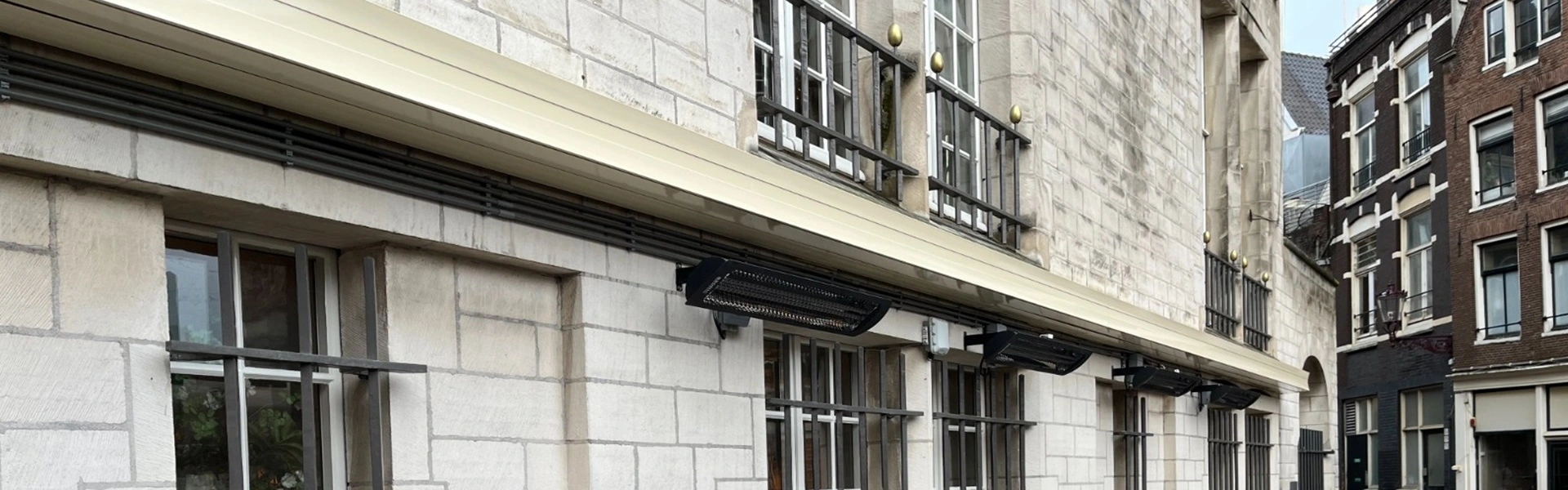 Zonwering met strak design boven ramen aan historische gevel
