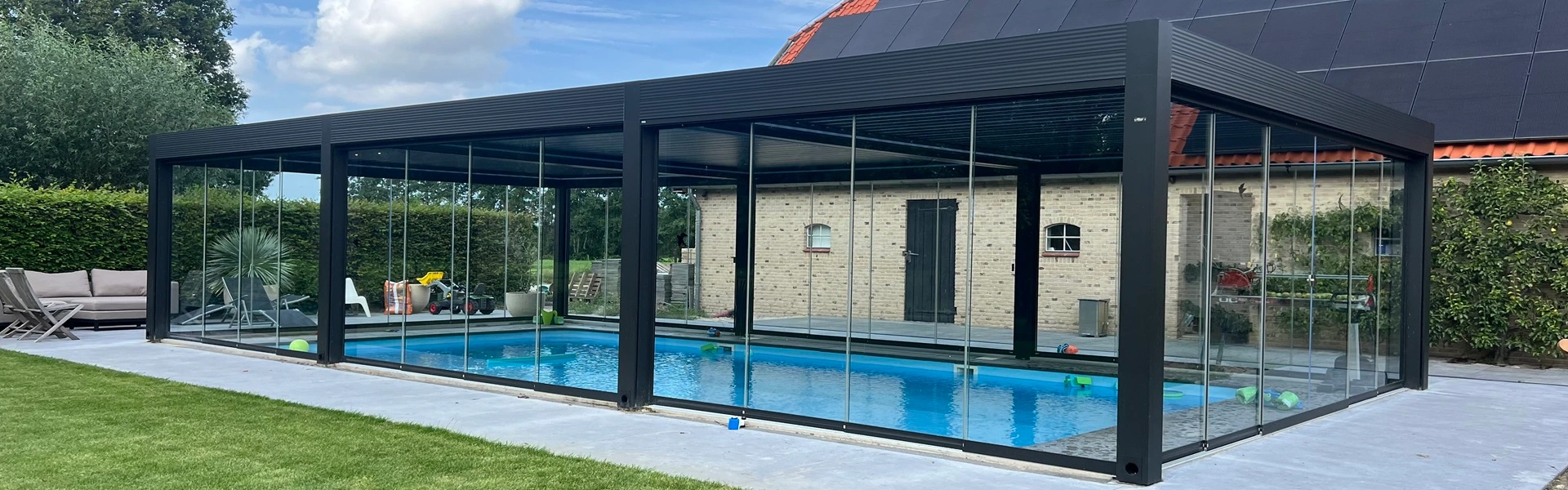 Zwarte aluminium tuinkamer met glazen schuifwanden over zwembad