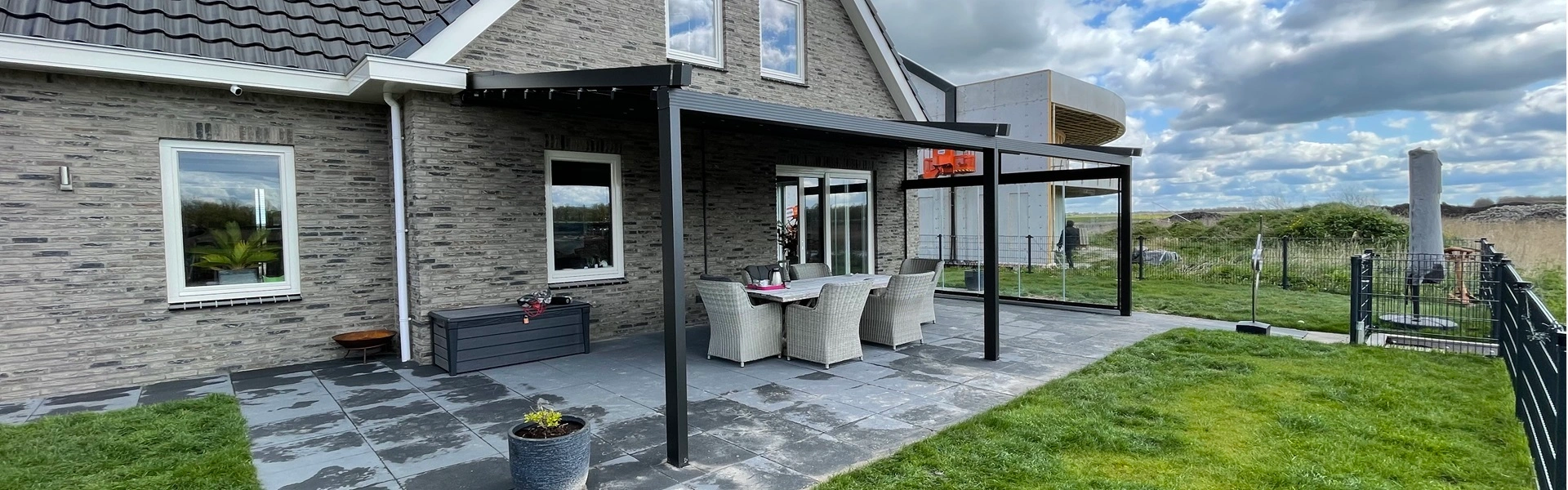 Zwarte overkapping aan woning met tuin en open uitzicht