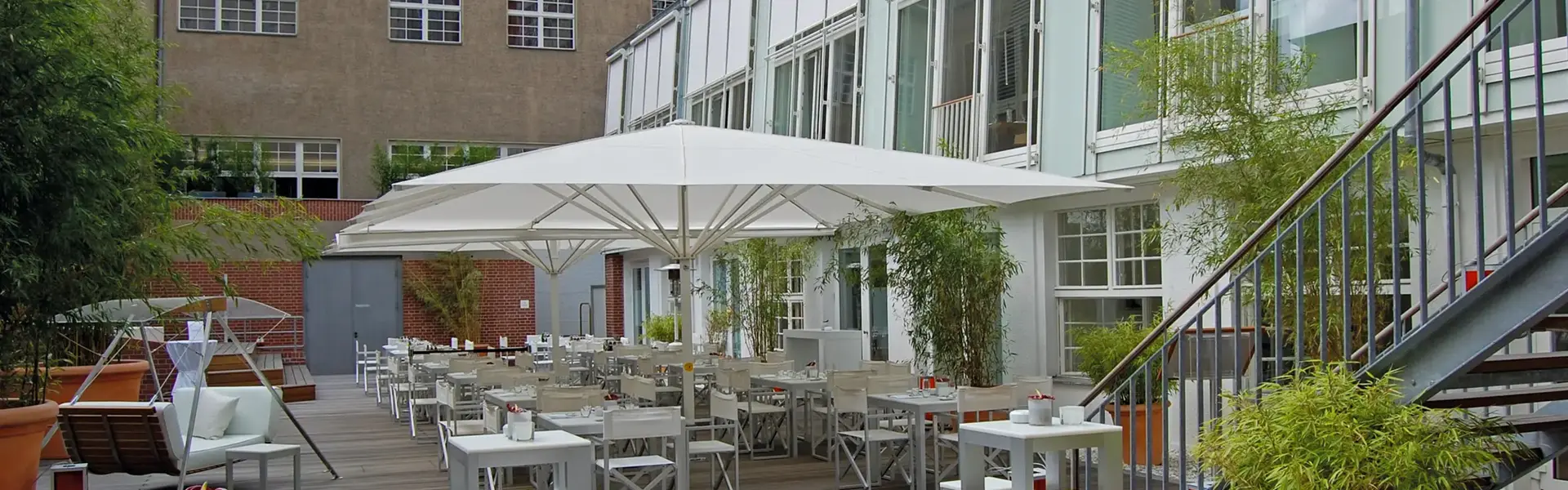 Albatros parasols op een plein met historische gebouwen en terrasstoelen