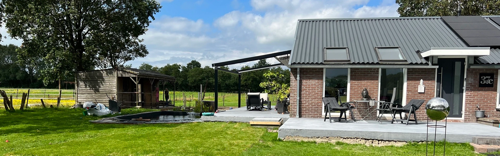 Aluminium terrasoverkapping naast een landelijke woning met uitzicht op groen