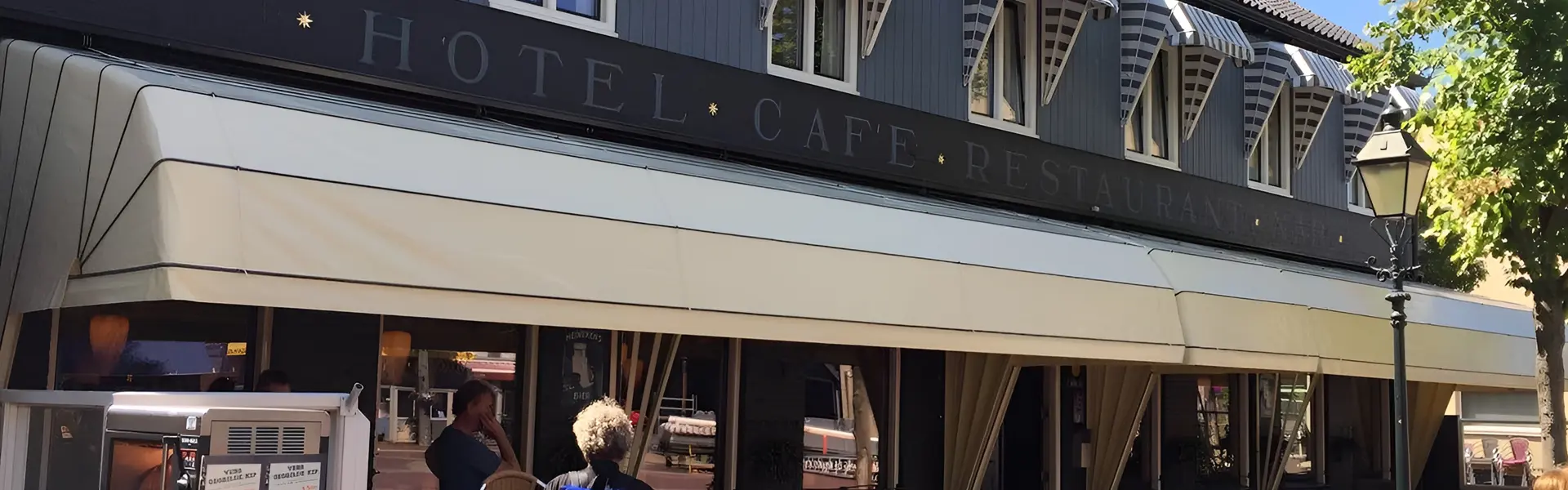 Cafe Nap met brede witte aluminium markiezen en straatzicht