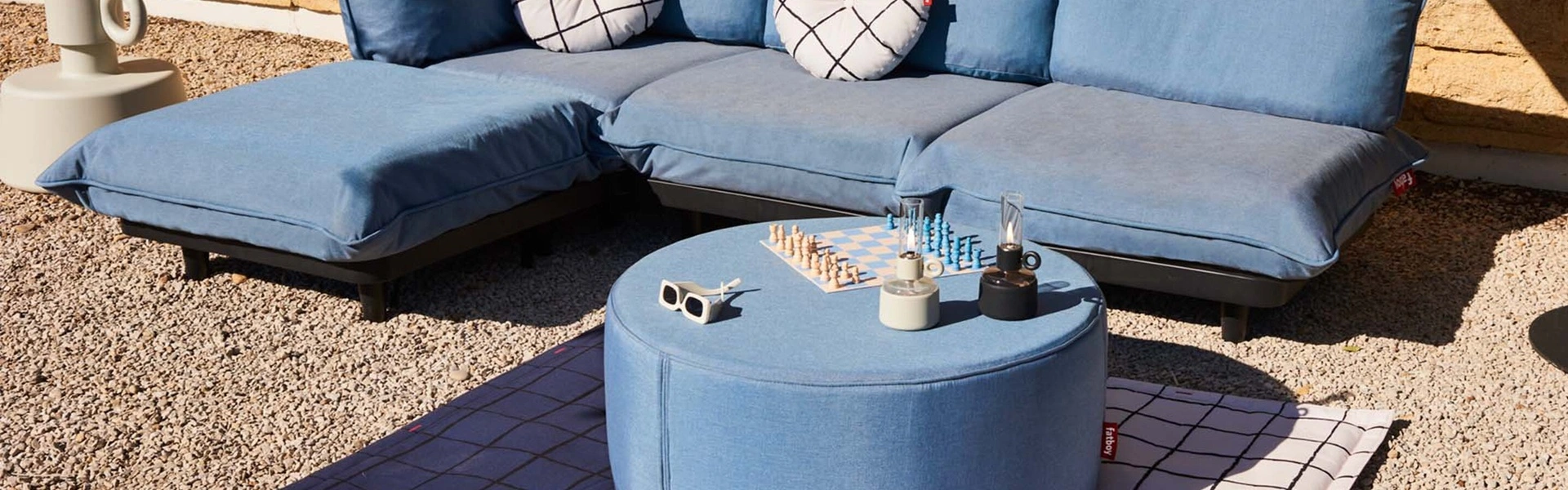 Fatboy buiten poef in blauw naast een loungebank met een schaakbord