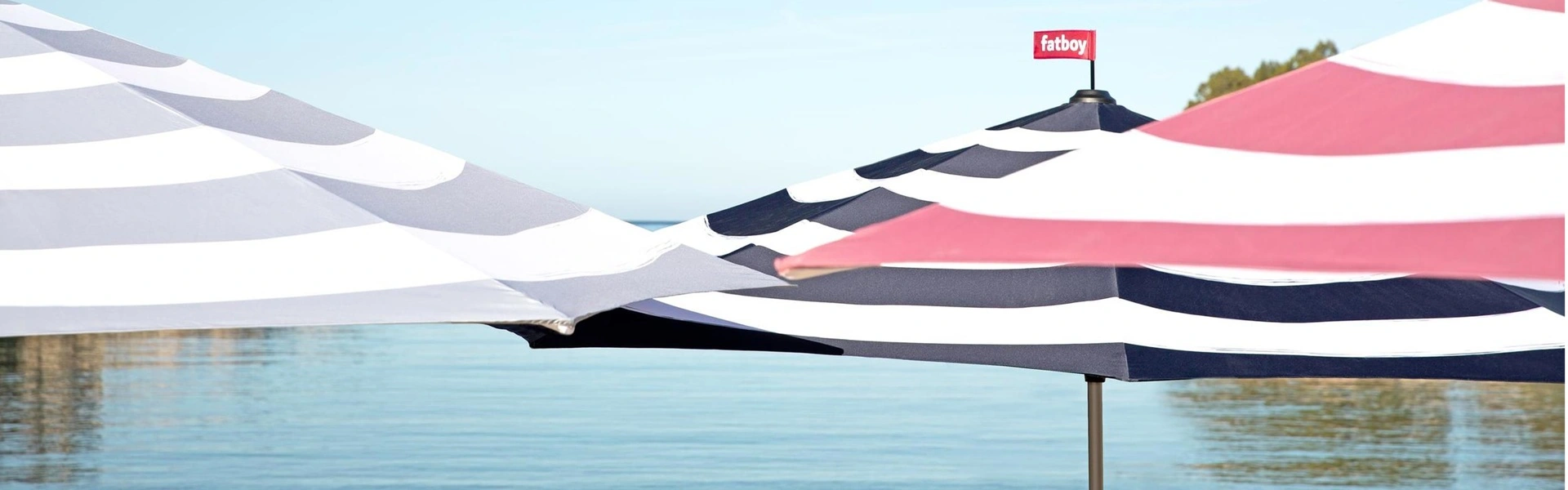 Gestreepte Fatboy parasols aan een rustige waterkant