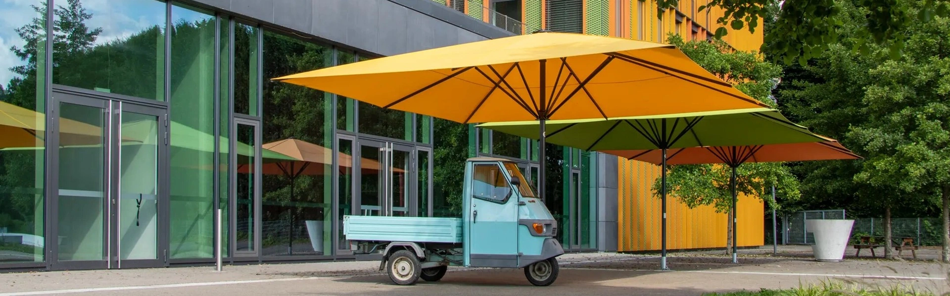 Grote gele en groene parasols Schatello voor een kleurrijk gebouw