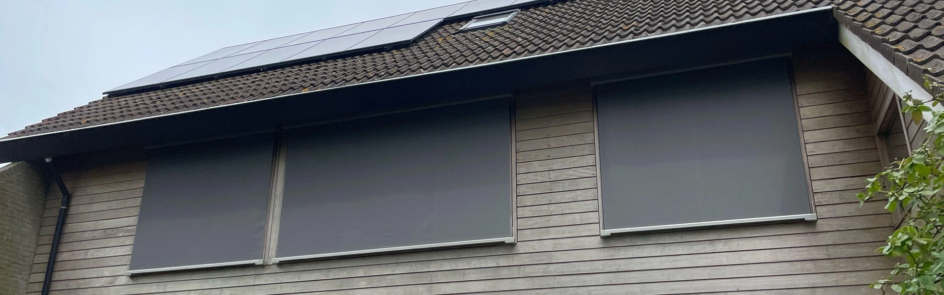 Houten gevel met kabelscreens en zonnepanelen op het dak