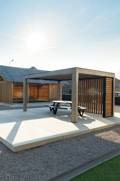 Houten overkapping met lamellen en picknicktafel op een betegeld terras Houten overkapping met lamellen en picknicktafel op een betegeld terras