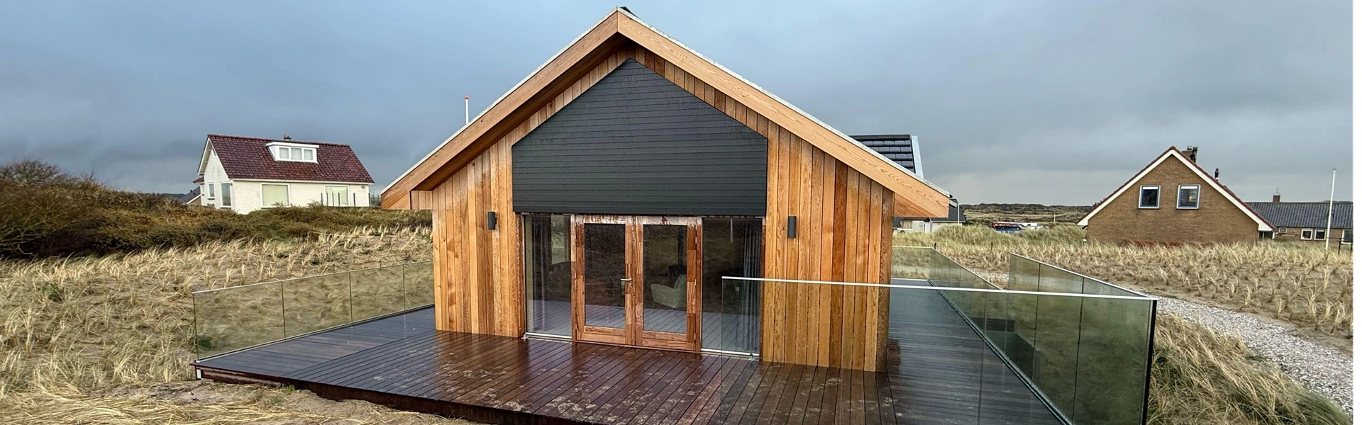 Houten woning met louvre zonwering in duinlandschap