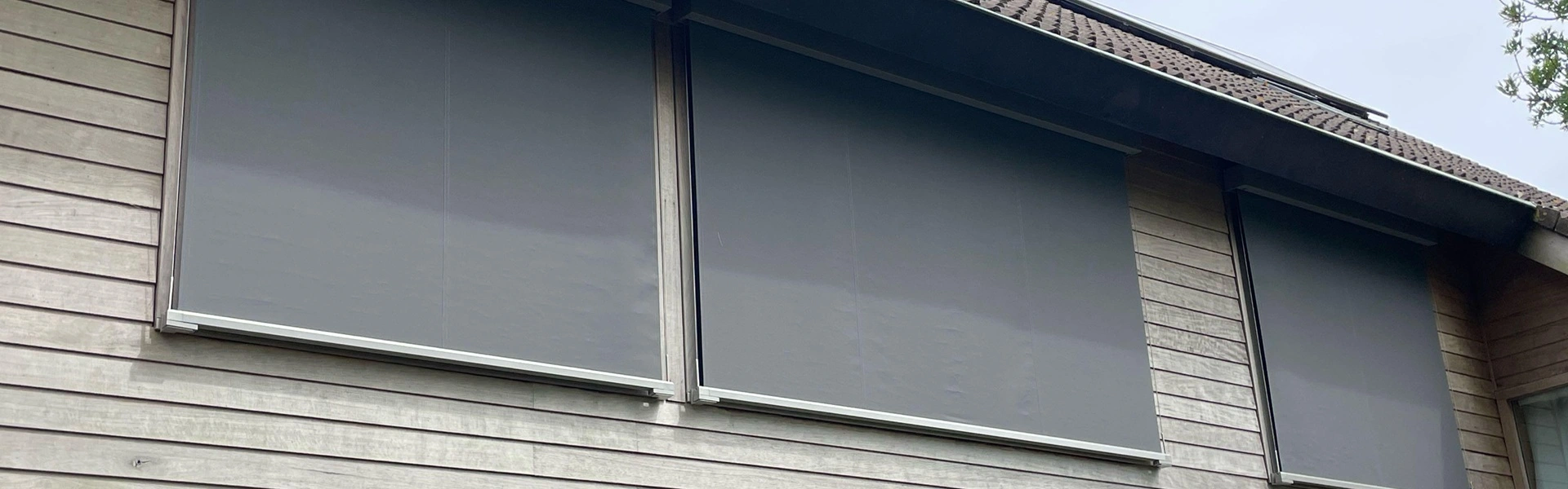 Kabelscreens op houten gevel van woning met schuine daklijn