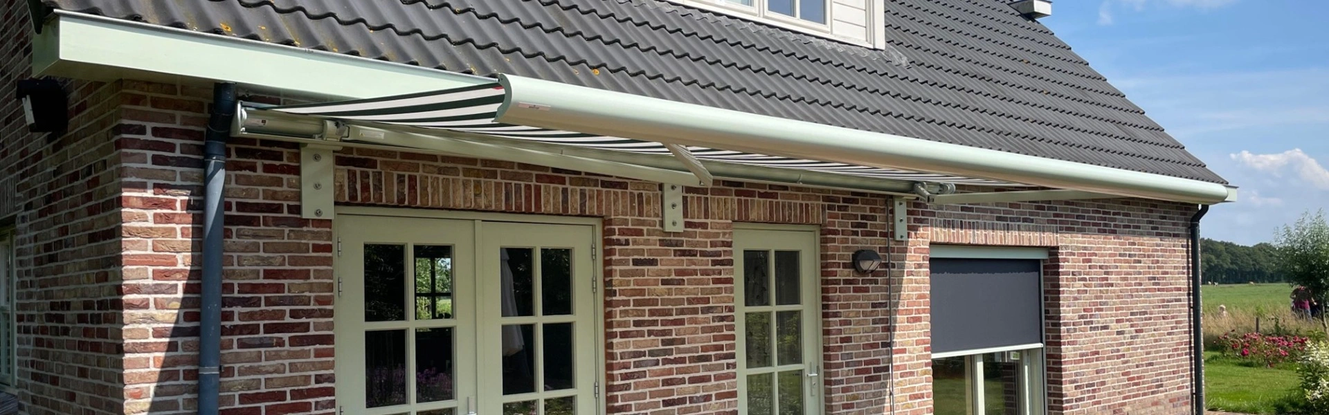 Knikarmscherm Opal in lichtgroen volledig geopend boven terras met dubbele deuren