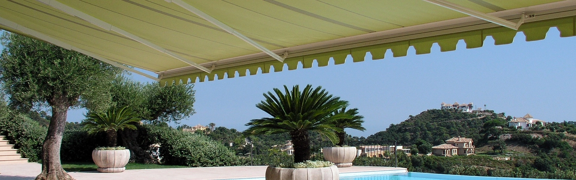 Lichtgroen knikarmscherm Jumbo boven terras met uitzicht op zwembad en heuvels