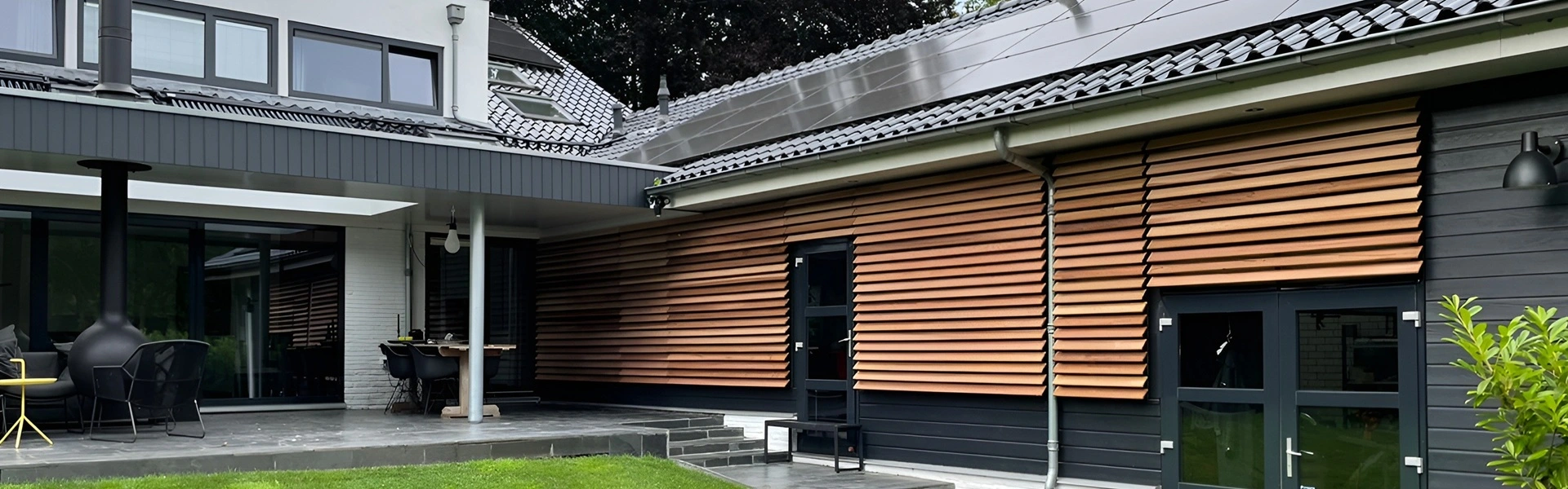 Louvers van hout geplaatst tegen een gevel met zonnepanelen