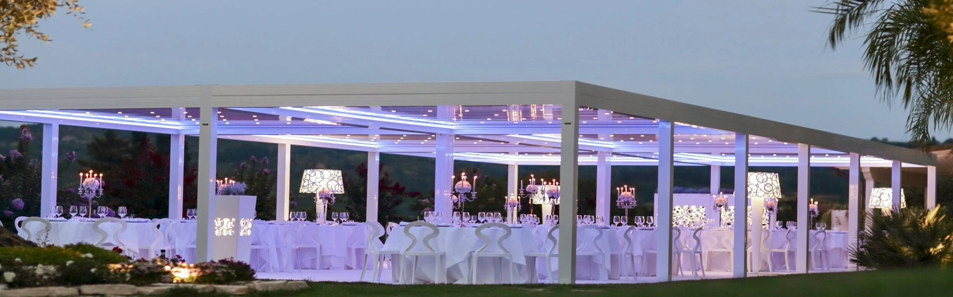 Overdekte openluchtlocatie met sfeervolle verlichting en wit interieur